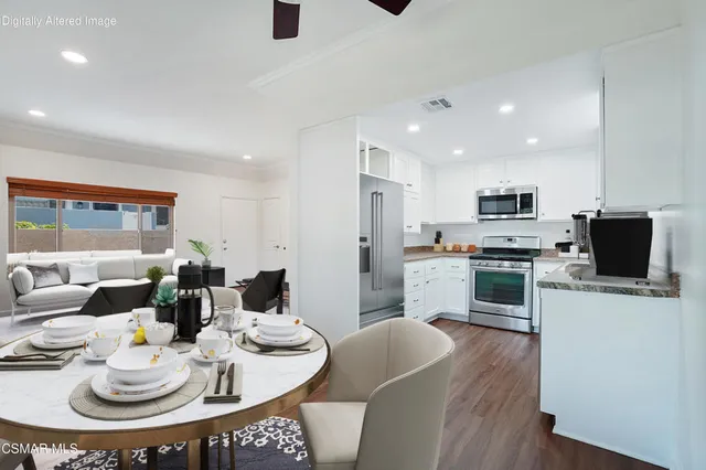 a kitchen with stainless steel appliances kitchen island granite countertop a dining table and chairs with wooden floor