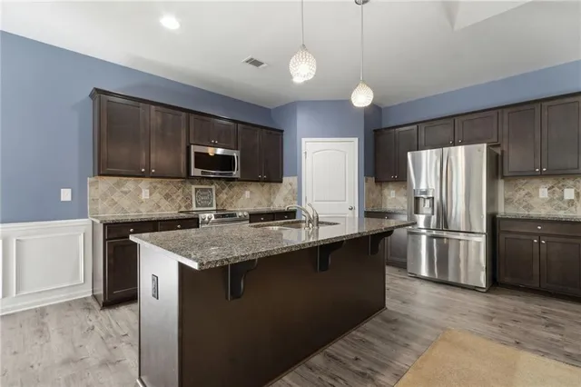 a kitchen with stainless steel appliances granite countertop a stove a sink a microwave a dining table and chairs