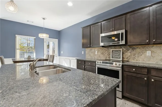 a kitchen with a stove a sink dishwasher a dining table and chairs with wooden floor