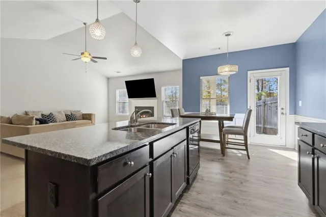 a large kitchen with granite countertop a sink a counter top space stainless steel appliances and cabinets