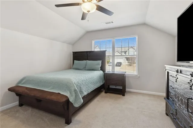 a bedroom with a bed and a flat tv screen on dresser