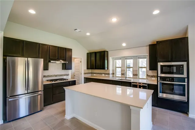 a large kitchen with stainless steel appliances kitchen island granite countertop a large counter top cabinets and a sink