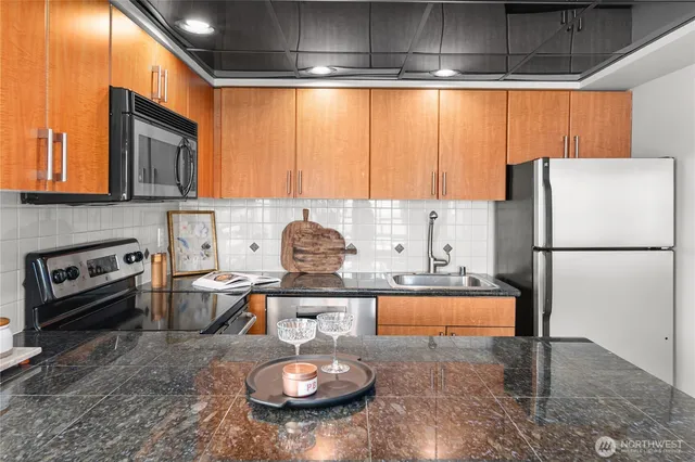 a kitchen with stainless steel appliances granite countertop a stove a refrigerator a sink a dining table and chairs with wooden floor