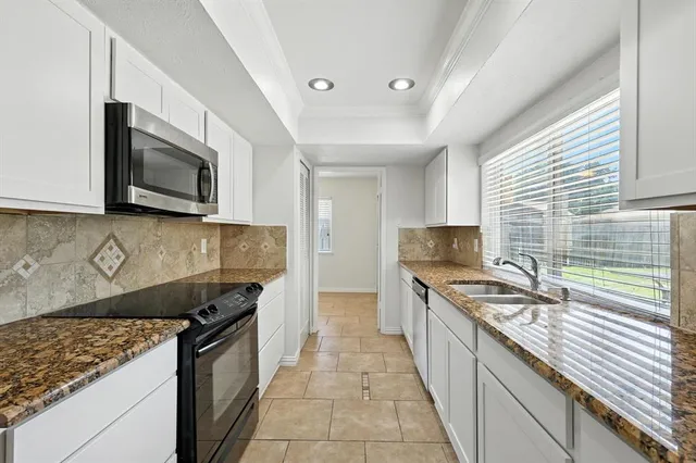 a kitchen with granite countertop stainless steel appliances a sink stove and microwave