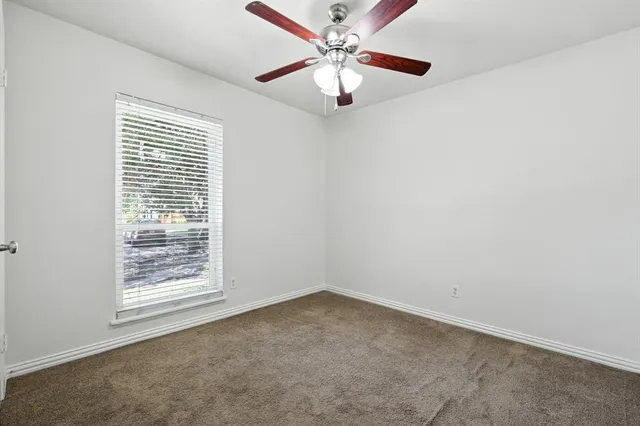 an empty room with a window and a fan