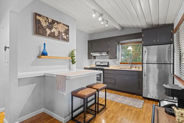 a kitchen with a refrigerator a stove a sink dishwasher and wooden cabinets with wooden floor