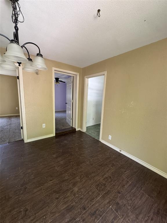 803 Ripley Avenue Ennis, TX 75119 - Photo 20 of 40 Spacious room featuring dark wood-finish flooring, neutral-toned walls, and a multi-light chandelier