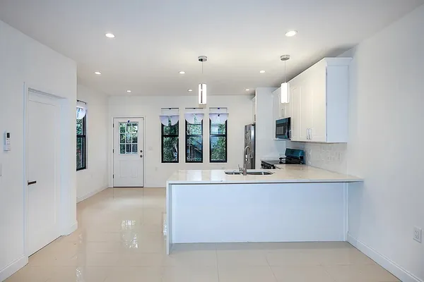 a large white kitchen with granite countertop a large counter top and stainless steel appliances