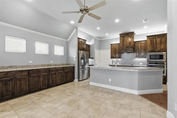a large kitchen with kitchen island granite countertop a sink counter space cabinets and stainless steel appliances