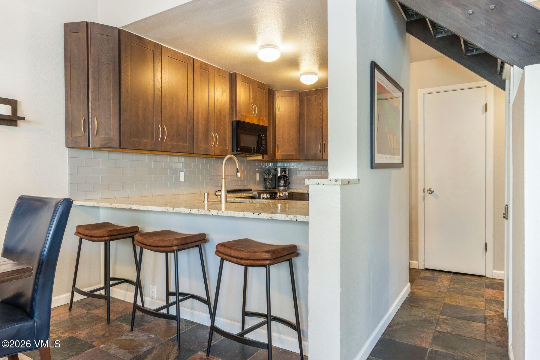 3911 Big Horn Road, Unit 1D Vail, CO 81657 - Photo 14 of 31 a kitchen with stainless steel appliances granite countertop a chairs a sink and a refrigerator