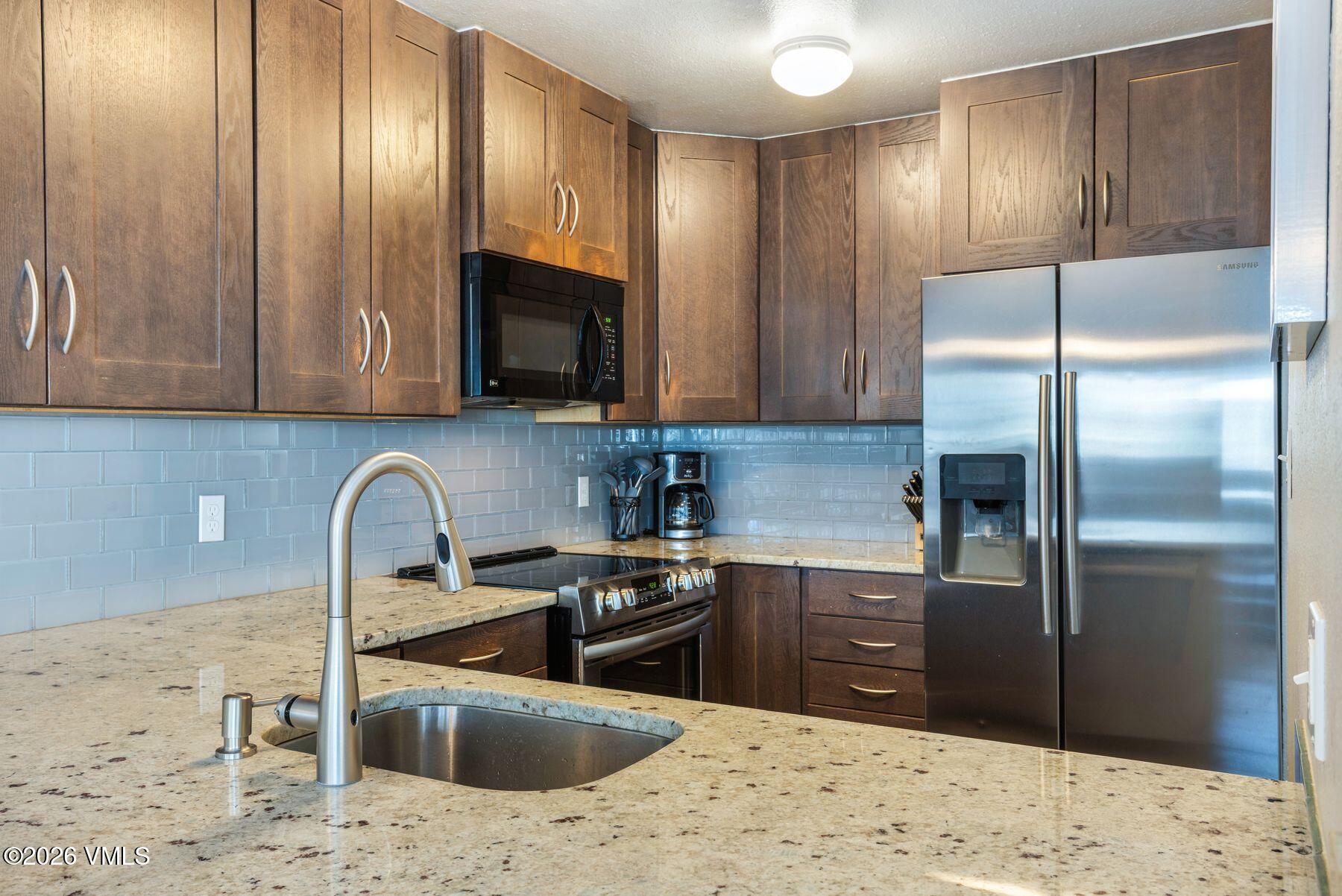3911 Big Horn Road, Unit 1D Vail, CO 81657 - Photo 15 of 31 a kitchen with stainless steel appliances granite countertop a sink stove and refrigerator
