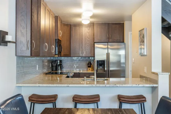a kitchen with stainless steel appliances granite countertop a sink and a refrigerator