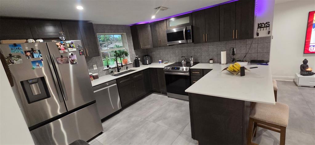 146 Marsella Road DeBary, FL 32713 - Photo 4 of 9 a kitchen with stainless steel appliances a stove refrigerator sink and microwave