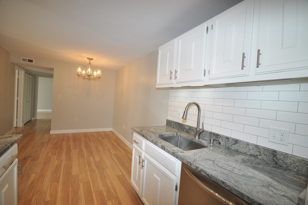 8 Walden Drive, Unit 13 Natick, MA 01760 - Photo 9 of 38 a view with granite countertop a sink dishwasher a stove and cabinets with wooden floor