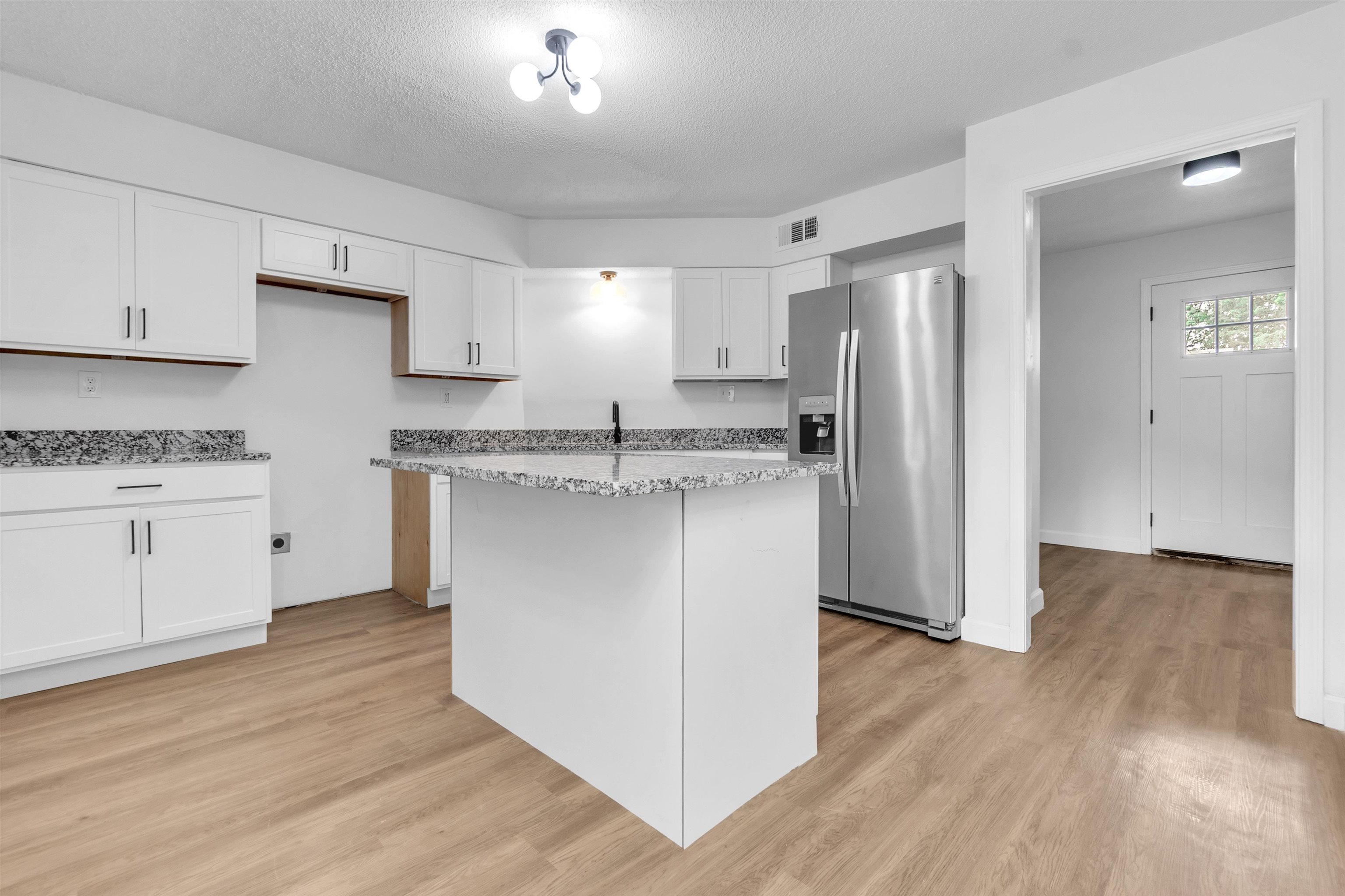 488 West Regis Place Memphis, TN 38018 - Photo 5 of 17 Kitchen featuring stainless steel refrigerator with ice dispenser, white cabinetry, light wood finished floors, a center island, and a textured ceiling