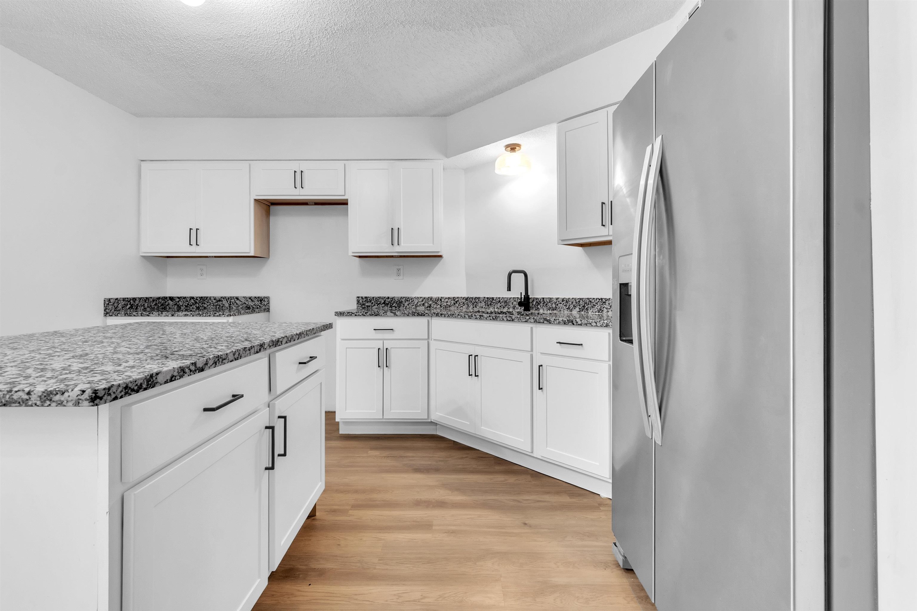 488 West Regis Place Memphis, TN 38018 - Photo 6 of 17 Kitchen with stainless steel fridge with ice dispenser, white cabinetry, light wood-type flooring, a textured ceiling, and dark stone counters