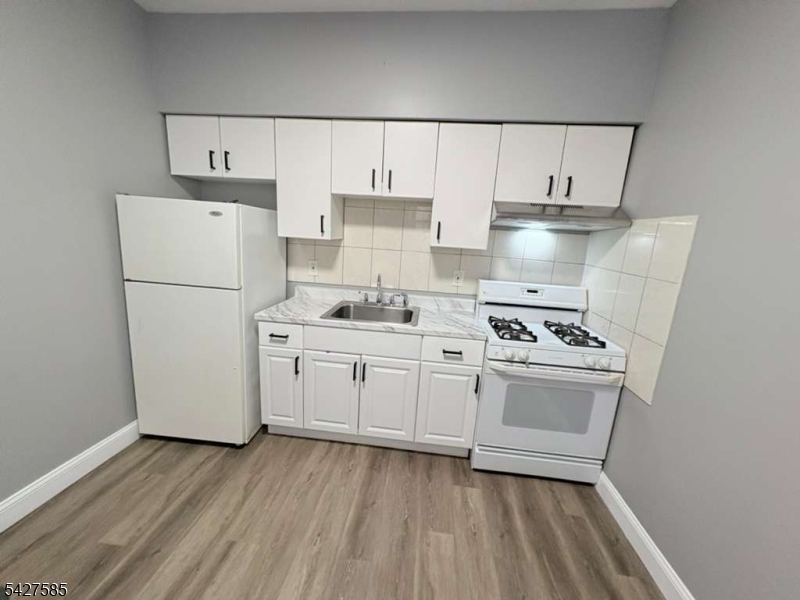 70 Main Street Garfield, NJ 07026 - Photo 7 of 9 a kitchen with a refrigerator a stove and white cabinets