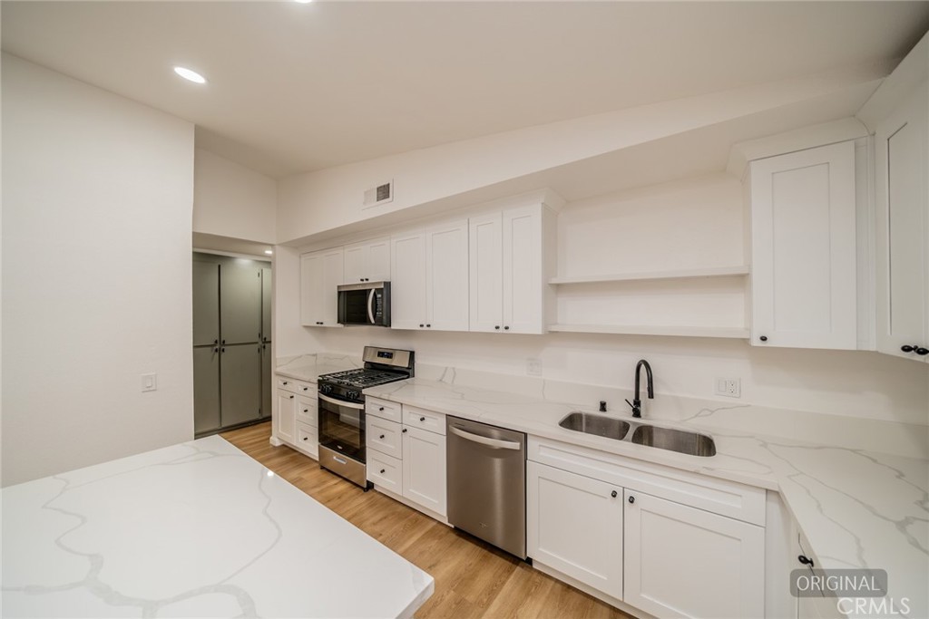 555 North Chestnut Avenue Rialto, CA 92376 - Photo 16 of 33 a kitchen with white cabinets and stainless steel appliances
