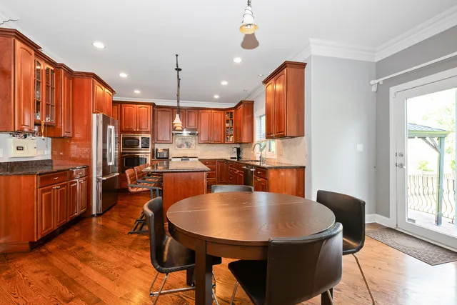 a kitchen with stainless steel appliances kitchen island granite countertop a sink dishwasher a stove a refrigerator with a dining table and chairs