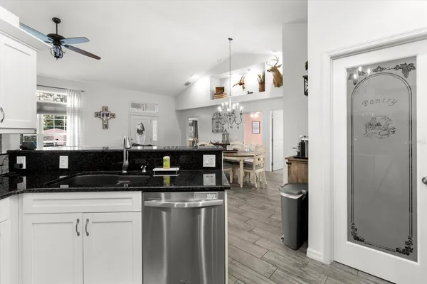 a kitchen with stainless steel appliances granite countertop a sink dishwasher a refrigerator and white cabinets with wooden floor