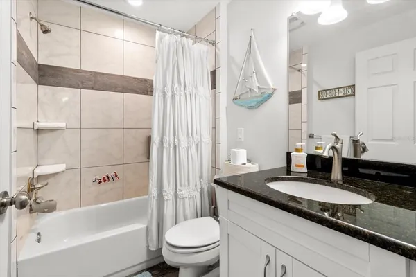 a bathroom with a granite countertop sink a toilet and bathtub