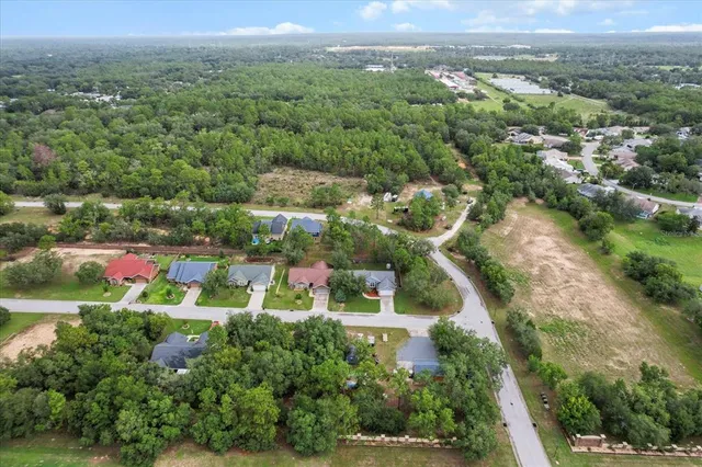 an aerial view of residential houses with outdoor space and trees