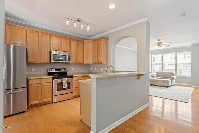 a kitchen with granite countertop a stove top oven a sink dishwasher a refrigerator cabinets and wooden floor