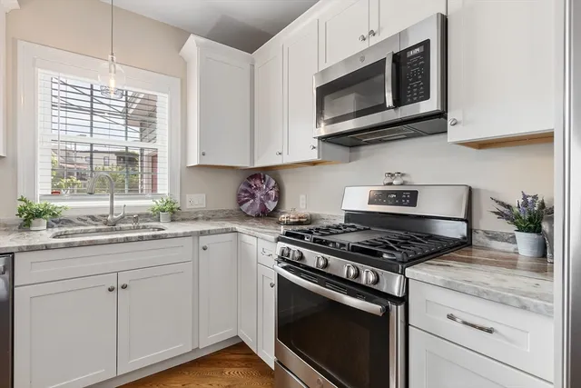 a kitchen with stainless steel appliances granite countertop white cabinets a sink and a stove