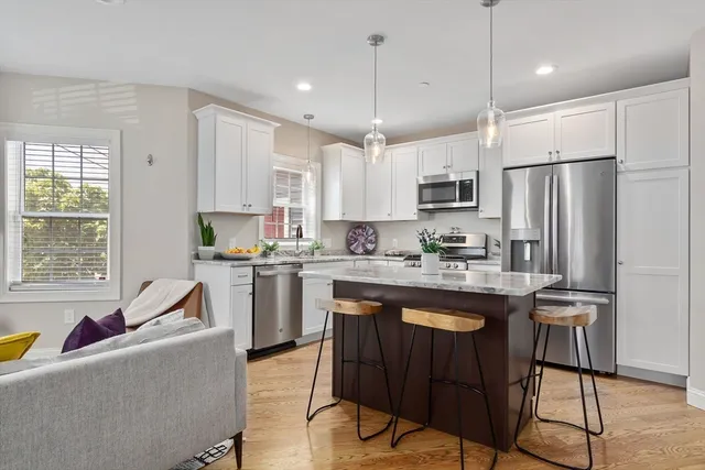 a kitchen with stainless steel appliances granite countertop a refrigerator a stove a sink a dining table and chairs