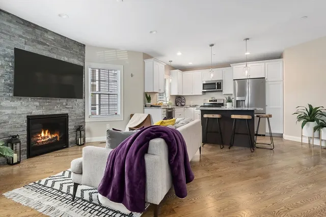 a view of kitchen with stainless steel appliances granite countertop a stove a sink dishwasher and a fireplace with wooden floor