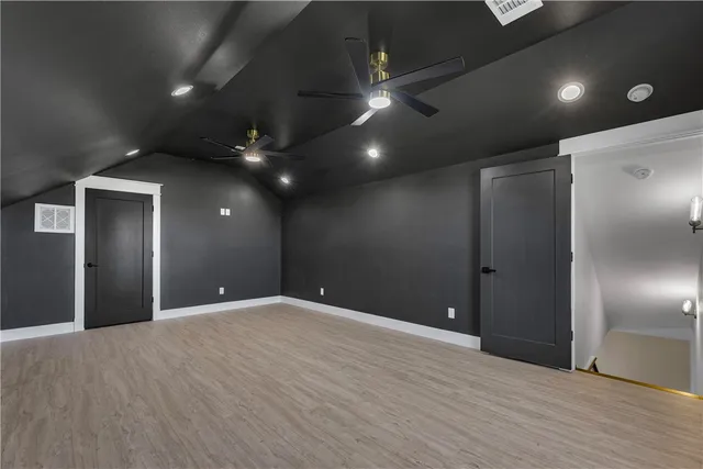 an empty room with ceiling fan and windows