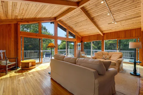 a living room with furniture floor to ceiling windows and wooden floor
