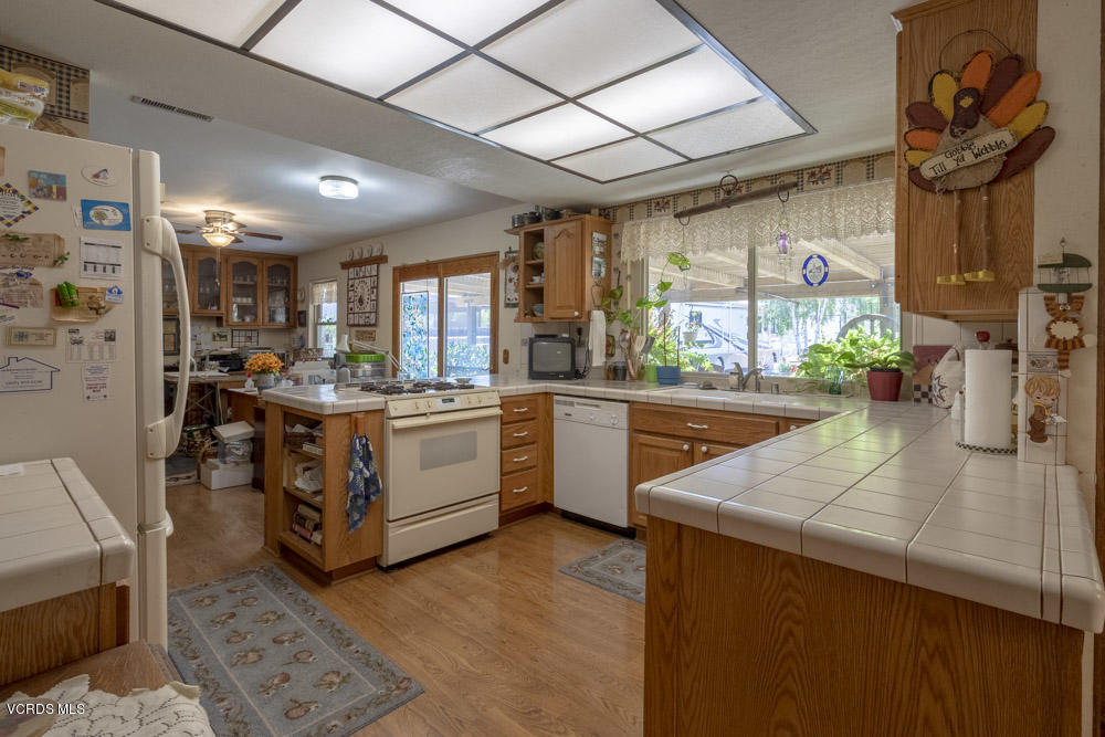 1642 Rambling Road Simi Valley, CA 93065 - Photo 8 of 39 a kitchen with stainless steel appliances granite countertop a stove a sink dishwasher and a refrigerator with wooden floor