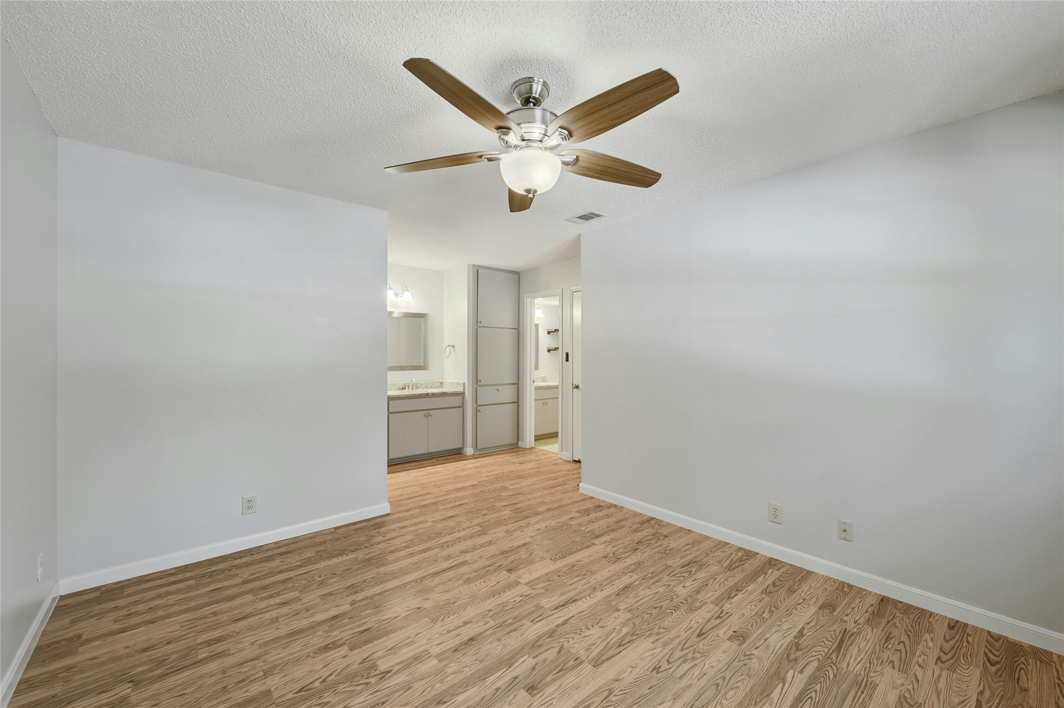 9226 Jollyville Road, Unit 221 Austin, TX 78759 - Photo 19 of 20 A well-lit primary bedroom featuring durable wood flooring and an elegant ceiling fan.