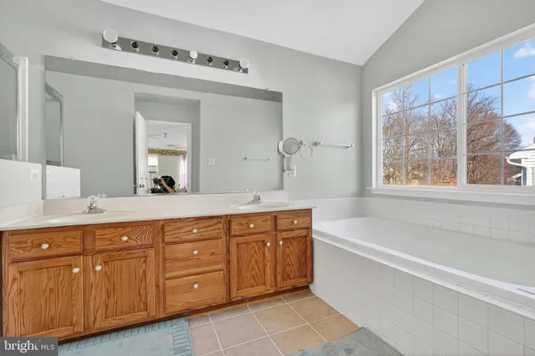 a spacious bathroom with a tub double sink window and mirror