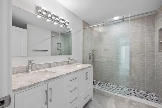a bathroom with a granite countertop sink a mirror a vanity and shower
