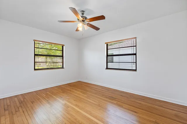 a view of a big room with wooden floor and windows