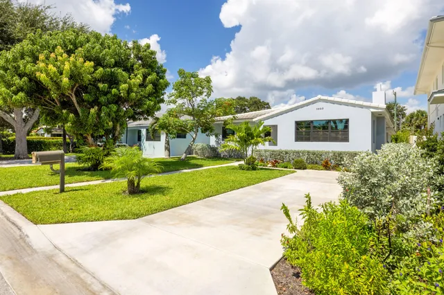a view of white house with a yard and potted plants