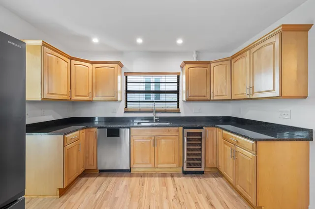 a kitchen with stainless steel appliances granite countertop a sink and cabinets with wooden floor
