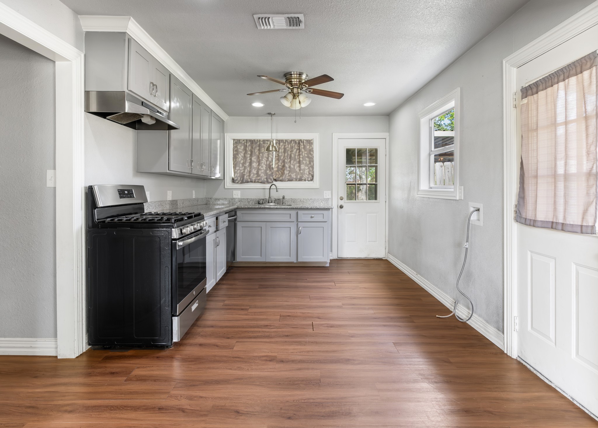 1921 Foote Street Wharton, TX 77488 - Photo 7 of 18 a kitchen with stainless steel appliances granite countertop a stove top oven a sink dishwasher and a refrigerator with wooden floor