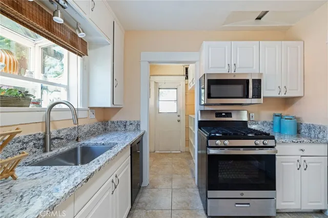 a kitchen with granite countertop a stove sink and microwave