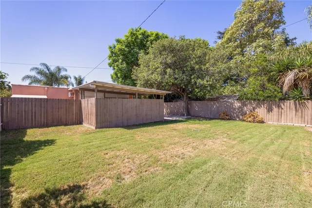 a view of a backyard with large tree and wooden fence