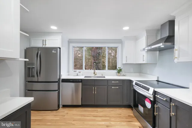 a kitchen with stainless steel appliances granite countertop a refrigerator a sink dishwasher a stove with wooden cabinets and floors