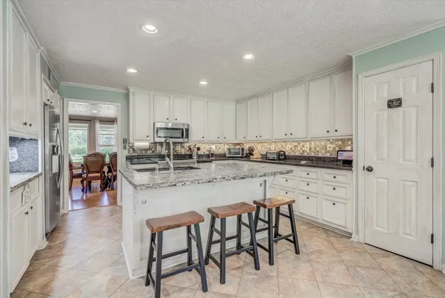 a kitchen with granite countertop sink stove and white cabinets