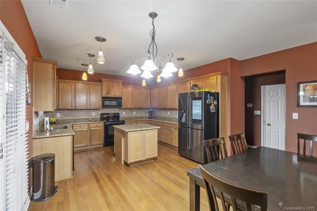 1559 Broderick Street Northwest Concord, NC 28027 - Photo 11 of 29 a kitchen with stainless steel appliances kitchen island granite countertop a refrigerator a stove top oven a sink dishwasher and white cabinets with wooden floor