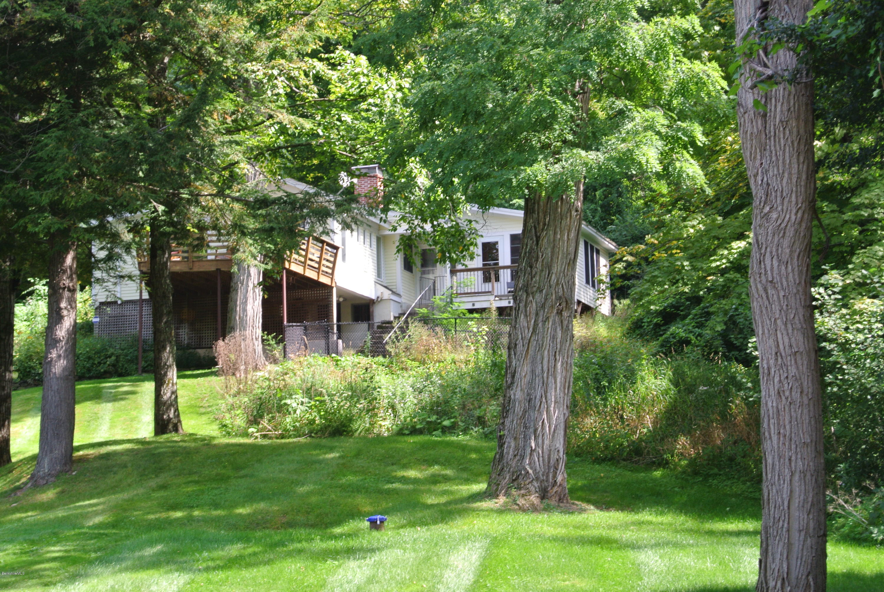 6 Mahkeenac Road Stockbridge, MA 01262 - Photo 1 of 20 a backyard of a house with plants and large tree