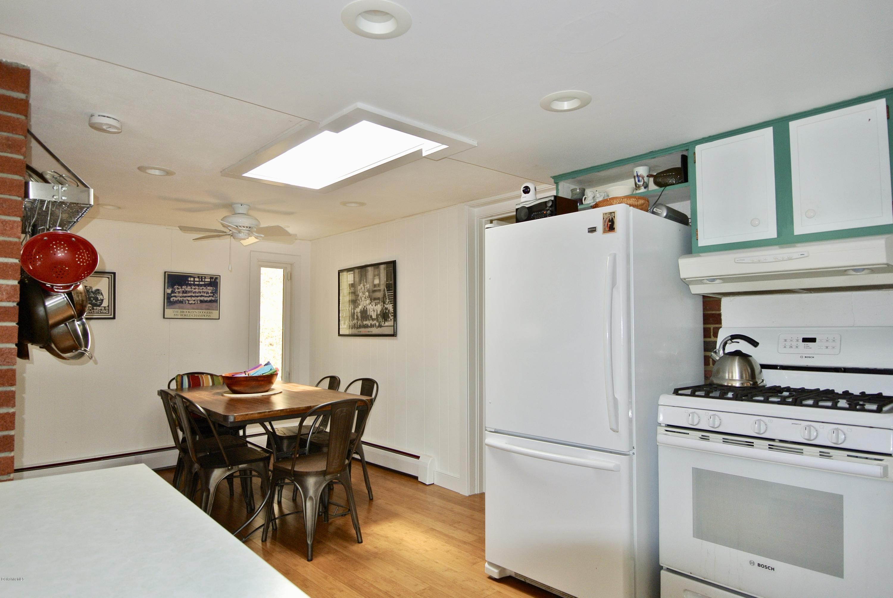 6 Mahkeenac Road Stockbridge, MA 01262 - Photo 8 of 20 a white kitchen with a refrigerator a stove a dining table and chairs with wooden floor