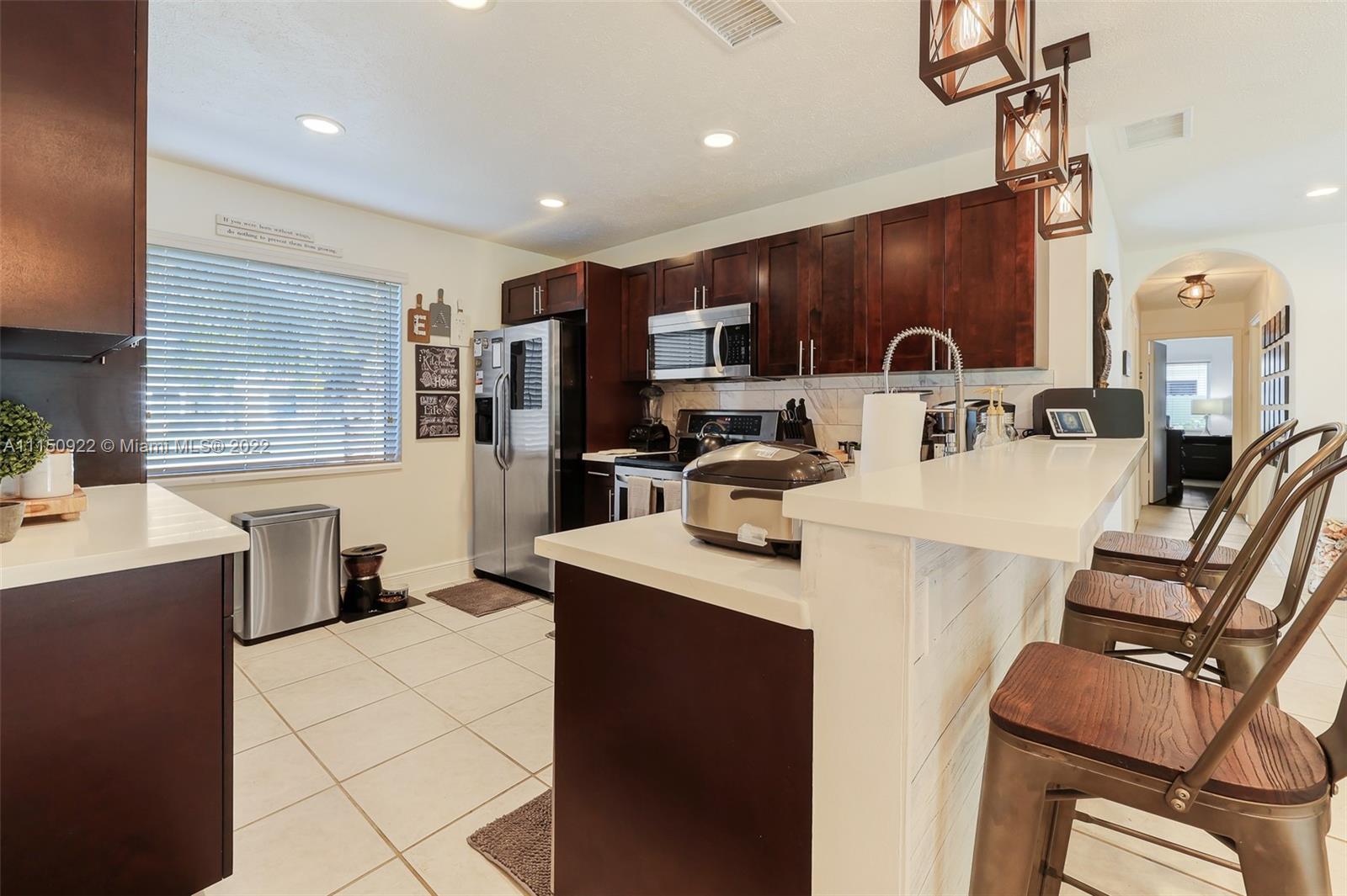 15534 Southwest 153rd Street Miami, FL 33187 - Photo 12 of 44 a kitchen with stainless steel appliances kitchen island granite countertop a stove a sink a refrigerator and a microwave