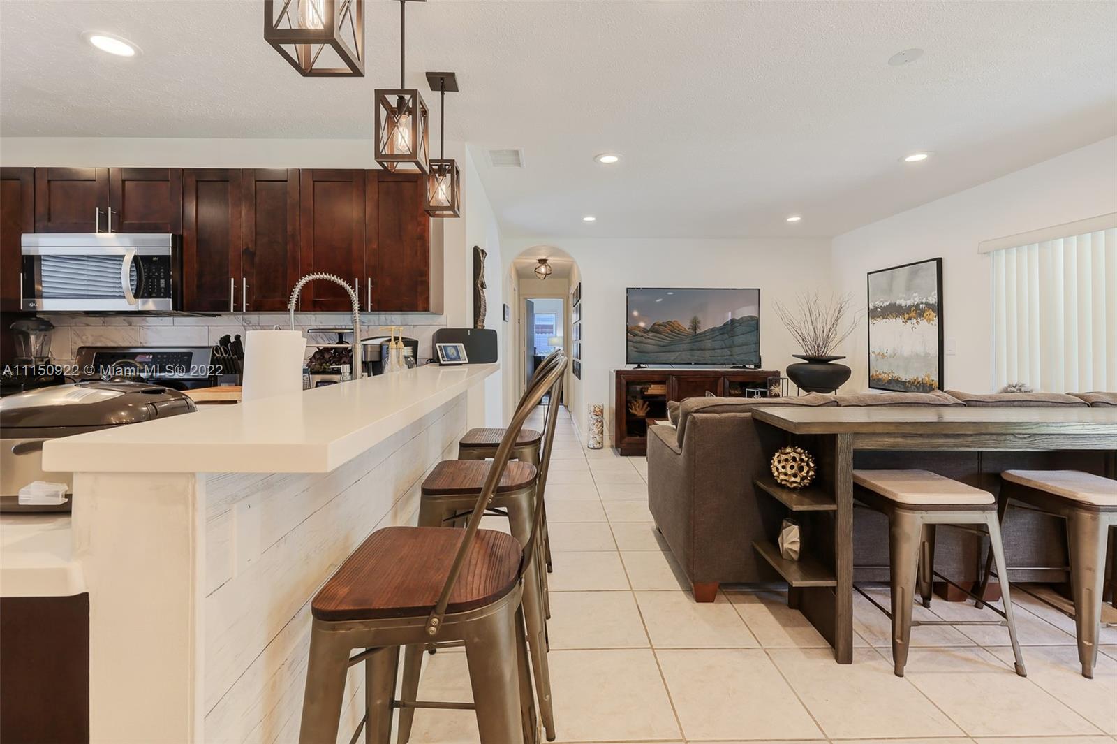 15534 Southwest 153rd Street Miami, FL 33187 - Photo 13 of 44 a kitchen with stainless steel appliances kitchen island granite countertop a stove a sink a dining table and chairs with wooden floor