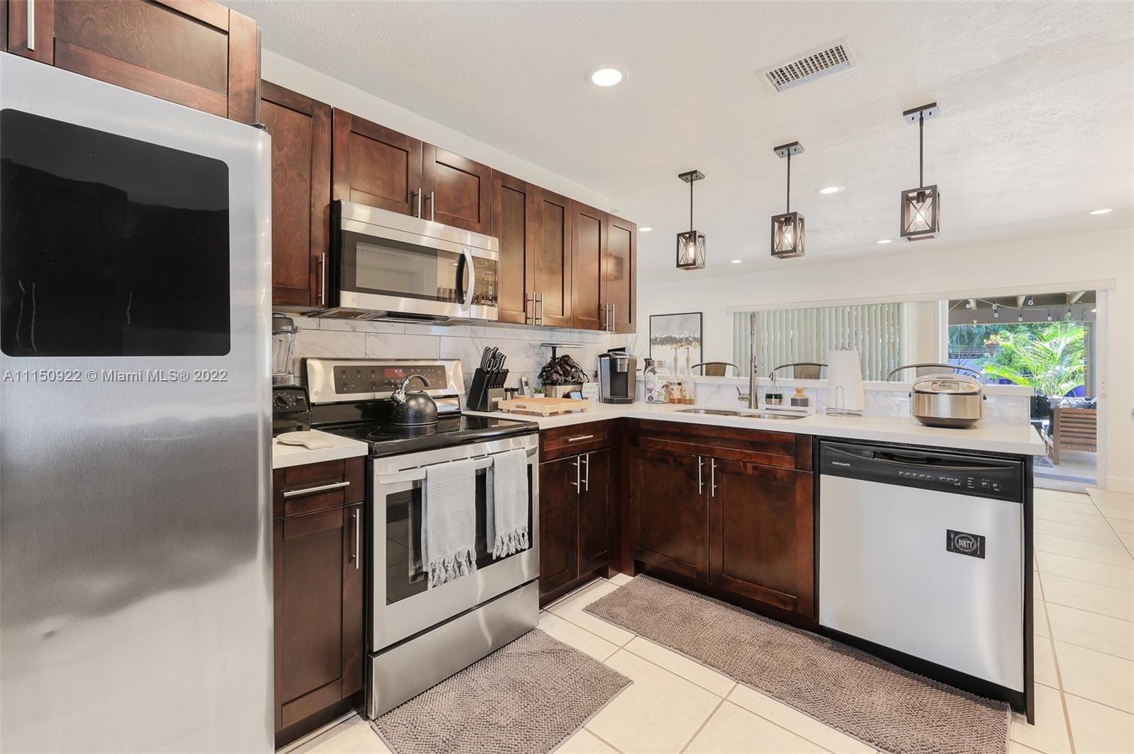 15534 Southwest 153rd Street Miami, FL 33187 - Photo 16 of 44 a kitchen with stainless steel appliances granite countertop a sink and a stove